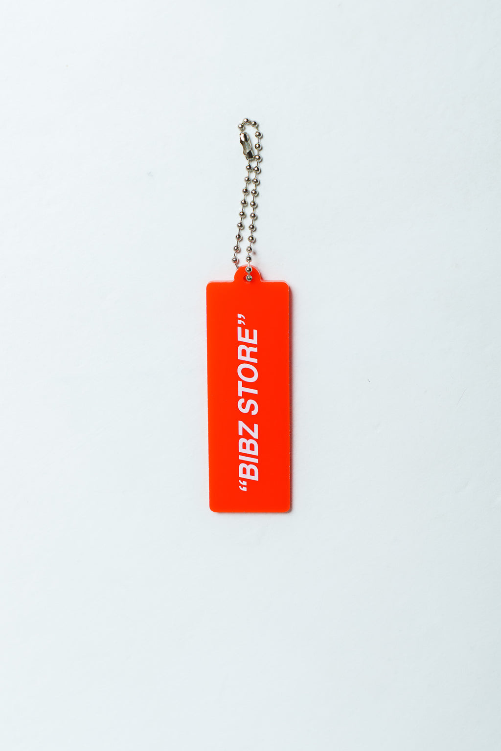 A bright red rectangular keychain tag with white text reading "BIBZ STORE" and a silver ball chain, centered on a plain white background.