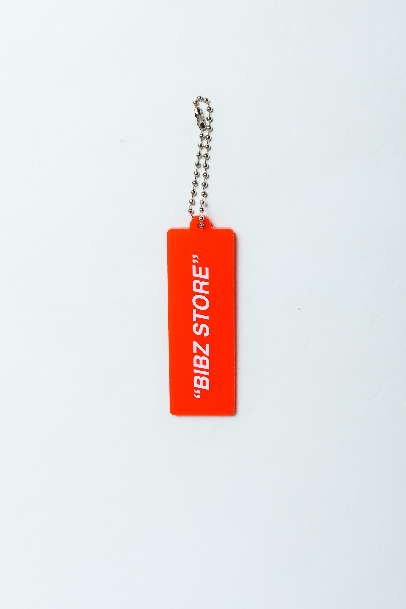 A bright red rectangular keychain tag with white text reading "BIBZ STORE" and a silver ball chain, centered on a plain white background.