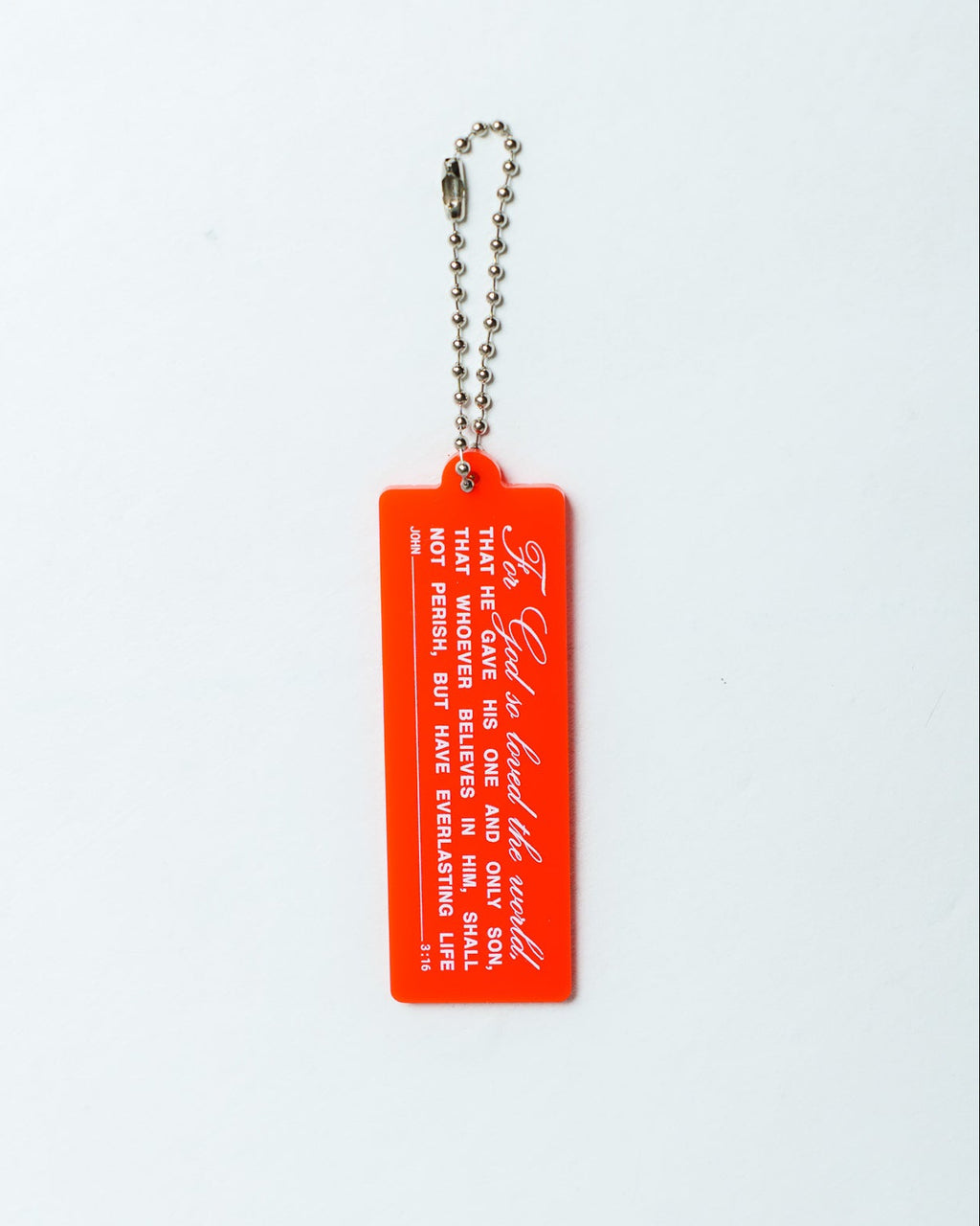 A bright red rectangular acrylic keychain tag featuring white printed text  with the Bible verse John 3:16 and script, attached to a silver ball chain, shown against a plain white background.