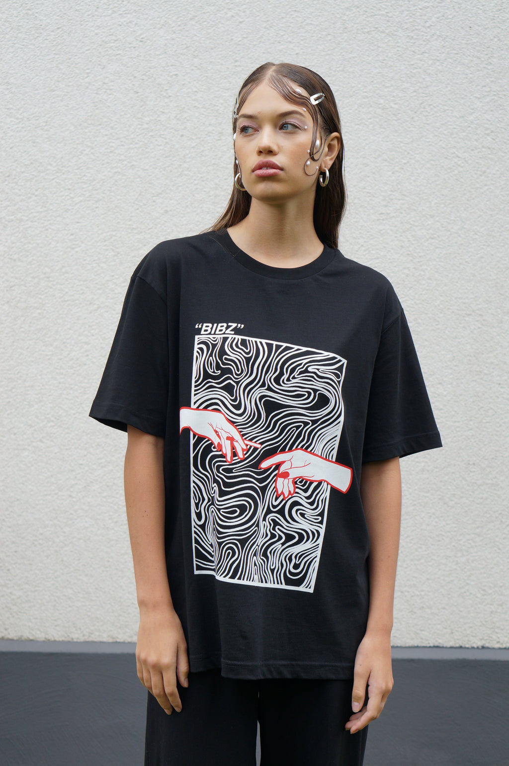 Person wearing a black t-shirt with a graphic design on a plain background