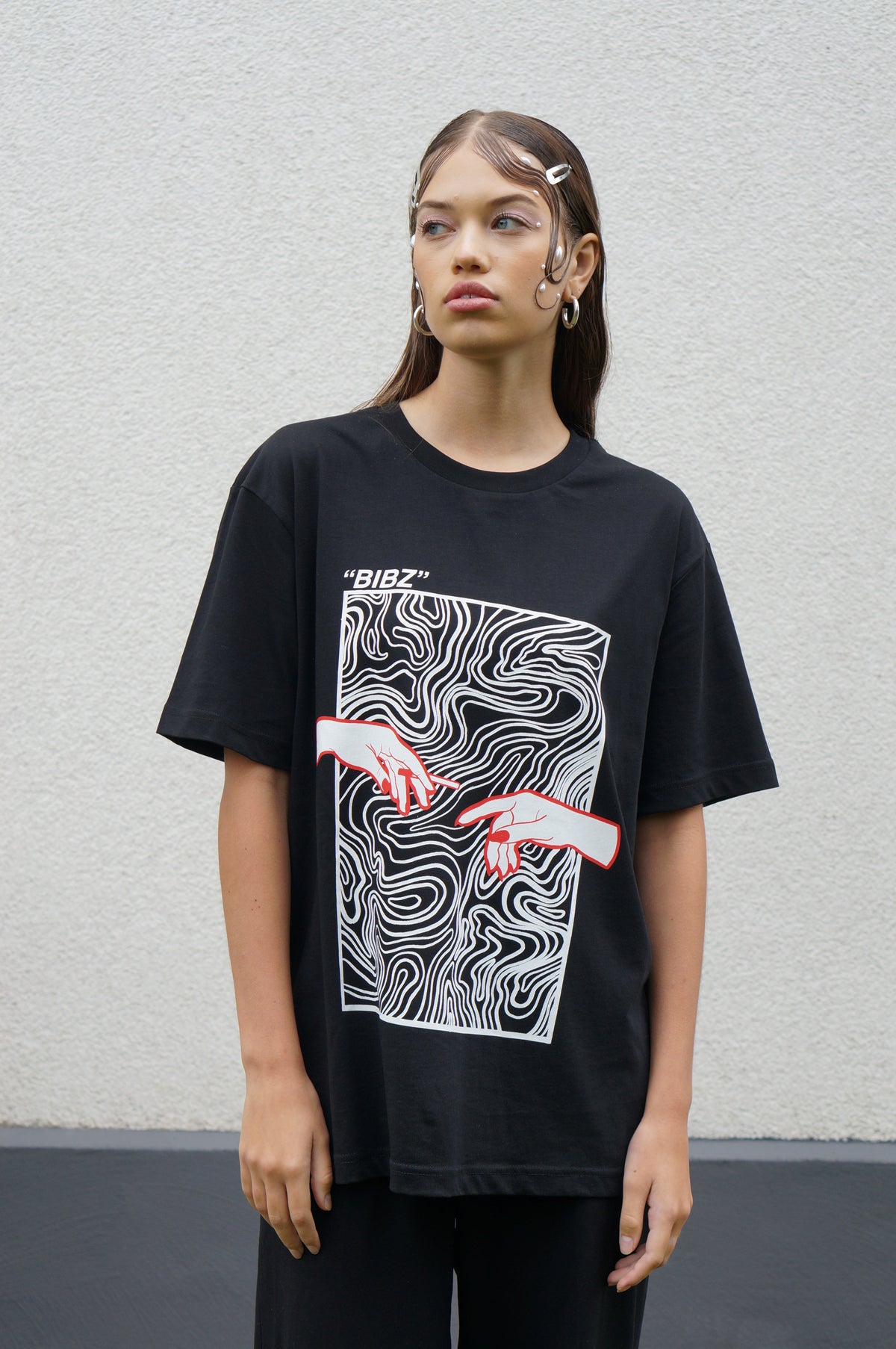 Person wearing a black t-shirt with a graphic design on a plain background