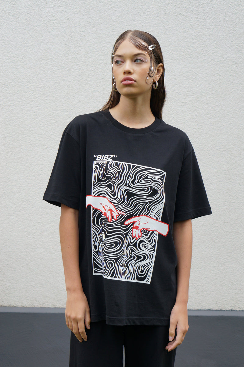 Person wearing a black t-shirt with a graphic design on a plain background